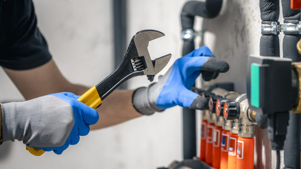 man installs heating system house checks pipes with wrench